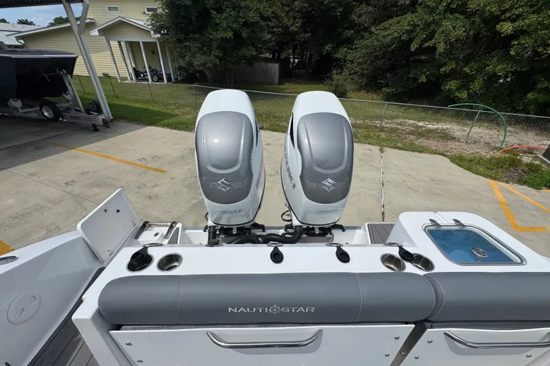 Slide: The Image of 2026 NauticStar 332 Offshore boat with dual outboard engines in a parking area. - 47