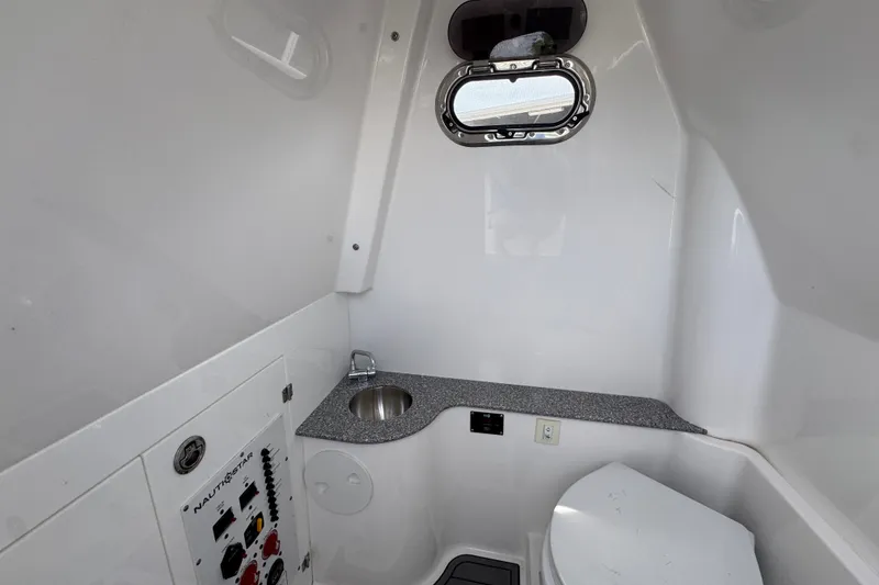 Slide: The Image of Interior of 2026 NauticStar 332 Offshore boat bathroom with sink and porthole. - 32