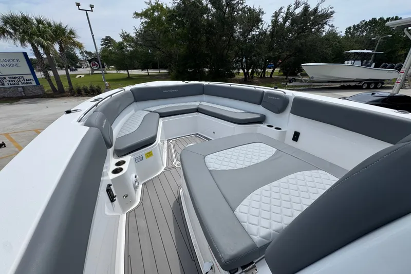 Slide: The Image of 2026 NauticStar 332 Offshore boat interior with gray seating and deck, parked outdoors. - 22