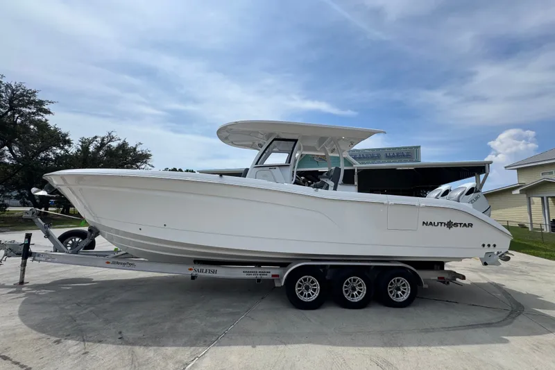 The Image of 2026 NauticStar 332 Offshore boat on trailer, parked outdoors under a cloudy sky. - 1