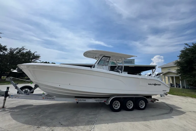 Slide: The Image of 2026 NauticStar 332 Offshore boat on trailer, parked outdoors under a cloudy sky. - 2
