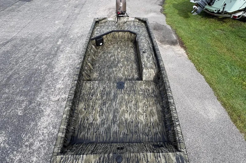 Slide: The Image of 2027 SeaArk DXS 1652 DKLD boat with camouflage interior, parked on pavement. - 14