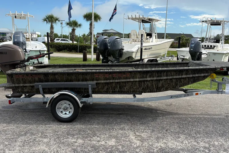 Slide: The Image of 2027 SeaArk DXS 1652 DKLD boat on trailer, camo design, parked outdoors. - 4