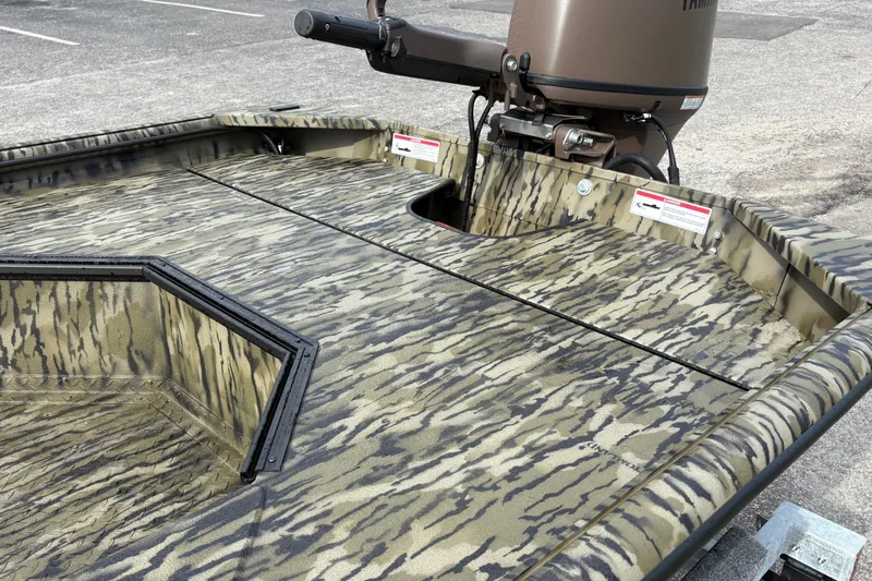 Slide: The Image of 2027 SeaArk DXS 1652 DKLD boat with camouflage design and motor, parked on concrete. - 7