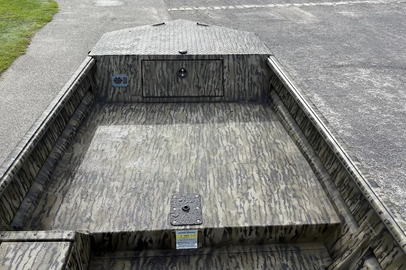 Slide: The Image of 2027 SeaArk DXS 1652 DKLD boat interior with camouflage pattern on a paved surface. - 12