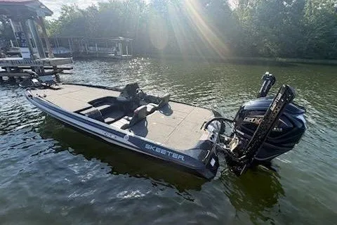 Slide: The Image of 2026 Skeeter ZXE20 boat on a calm lake near a dock, under sunlight. - 15