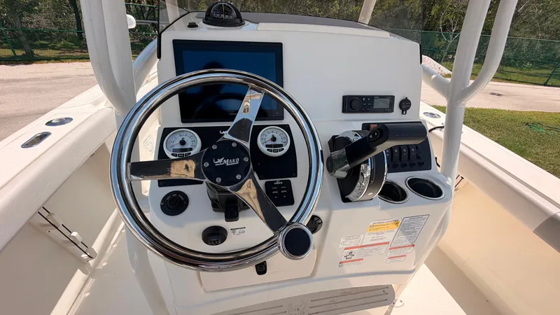 Slide: The Image of The image shows the helm of a 2024 Mako 214CC boat with a steering wheel and instruments. - 21