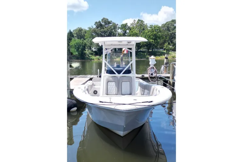Slide: The Image of 2022 Sea Fox 228 Commander boat docked on calm water, surrounded by greenery. - 2