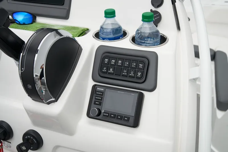 Slide: The Image of 2026 Tahoe 2150 CC boat dashboard with controls, cup holders, and water bottles. - 13