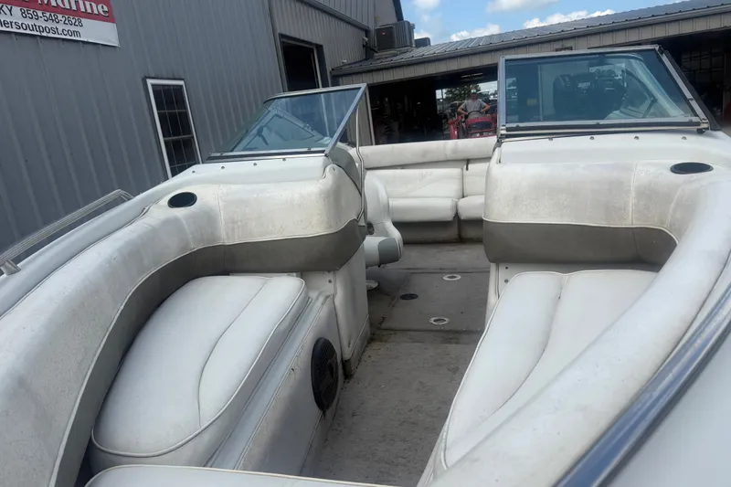 Slide: The Image of 2000 Crownline 202 BR boat interior with white seating and windshield, docked near a building. - 4