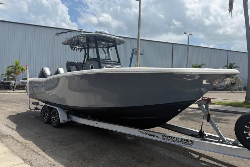 Slide: The Image of 2020 Tidewater 280 CC Adventure boat on trailer, parked outdoors under cloudy sky. - 2