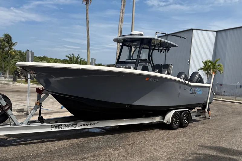 Slide: The Image of 2020 Tidewater 280 CC Adventure boat on trailer, parked outdoors near palm trees. - 1