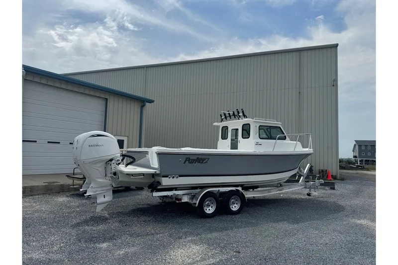 Slide: The Image of 2027 Parker 247 Explorer boat on trailer, parked outside a large warehouse. - 1