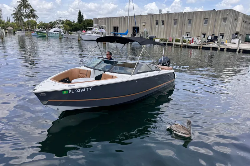 Slide: The Image of 2023 Four Winns H2 OB boat on water near dock, with pelican swimming nearby. - 1