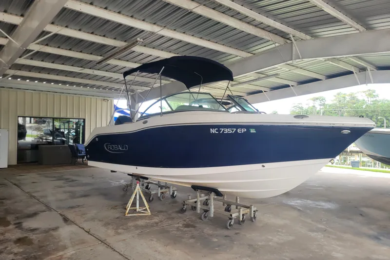 The Image of 2020 Robalo R207 Dual Console boat in covered storage, blue and white exterior. - 0