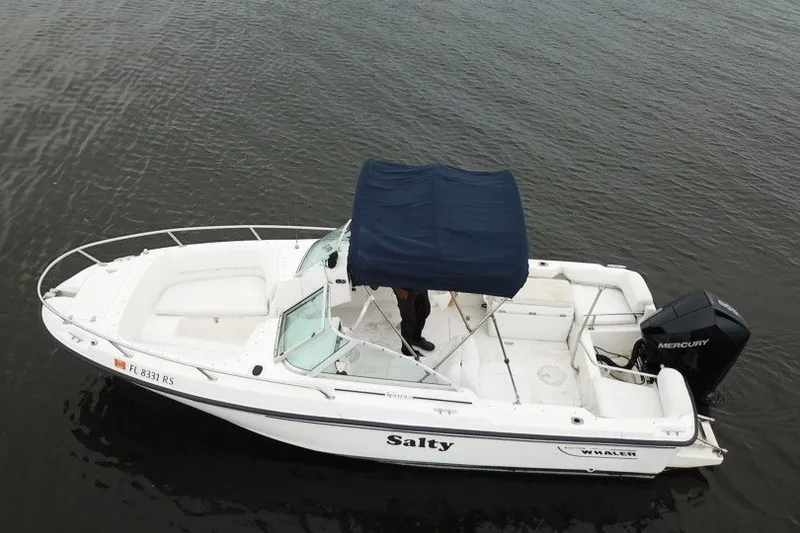 Slide: The Image of 1998 Boston Whaler 20 Ventura Bowrider with blue canopy on calm water. - 6