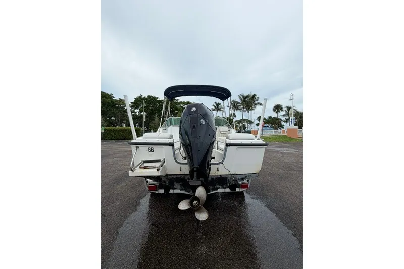 Slide: The Image of 1998 Boston Whaler 20 Ventura Bowrider with outboard motor, parked on wet pavement. - 14