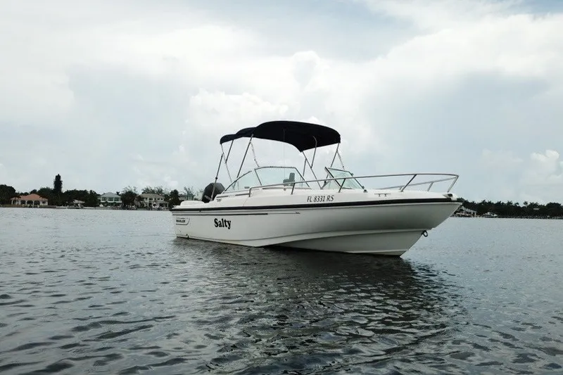 Slide: The Image of 1998 Boston Whaler 20 Ventura Bowrider on calm water, featuring a sleek design and canopy. - 9