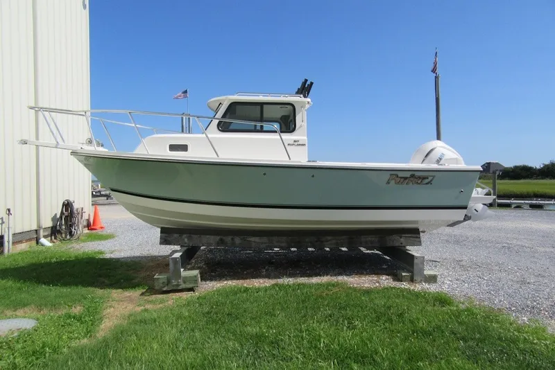 The Image of 2027 Parker 217 Explorer boat on display, outdoors, with American flags in the background. - 2