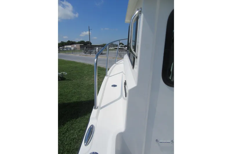 Slide: The Image of 2027 Parker 217 Explorer boat deck with railing, parked on grass under blue sky. - 8