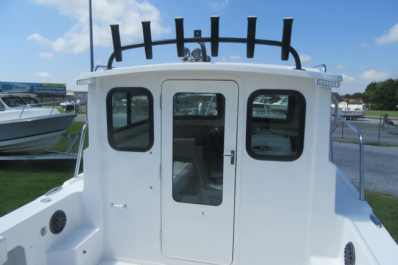 Slide: The Image of 2027 Parker 217 Explorer boat with enclosed cabin and rod holders, displayed outdoors. - 6