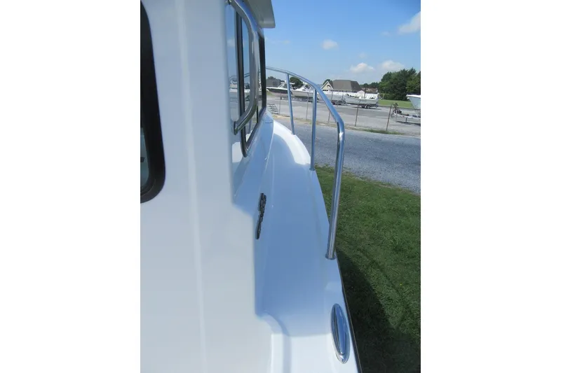 Slide: The Image of 2027 Parker 217 Explorer boat side view with railing, parked on grass. - 7
