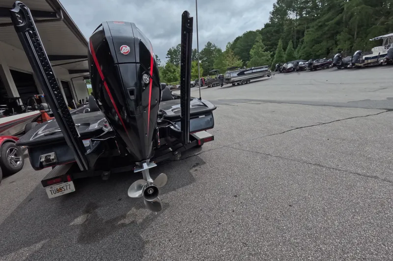 Slide: The Image of 2021 Caymas boat with powerful outboard motor in a parking area, surrounded by trees and trailers. - 30