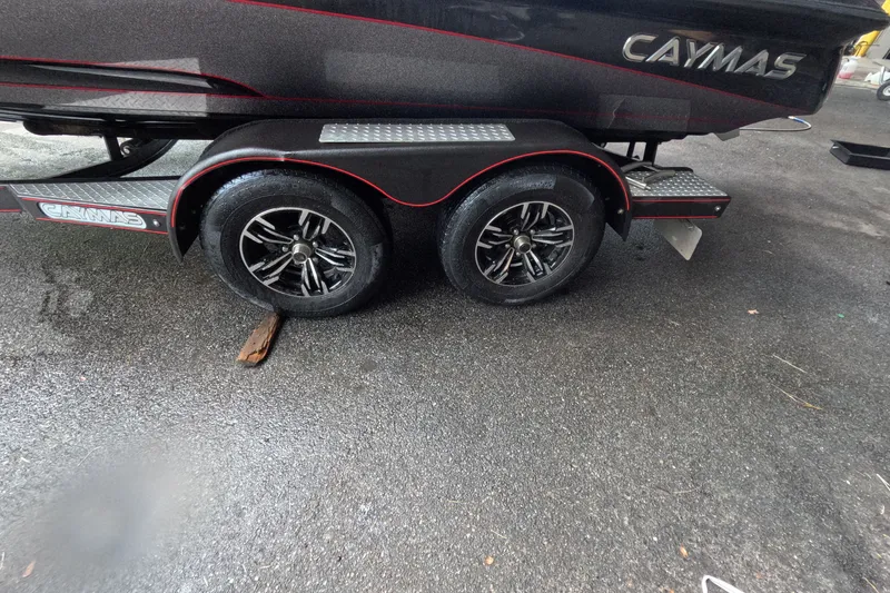 Slide: The Image of 2021 Caymas boat trailer with dual black wheels on wet pavement. - 13