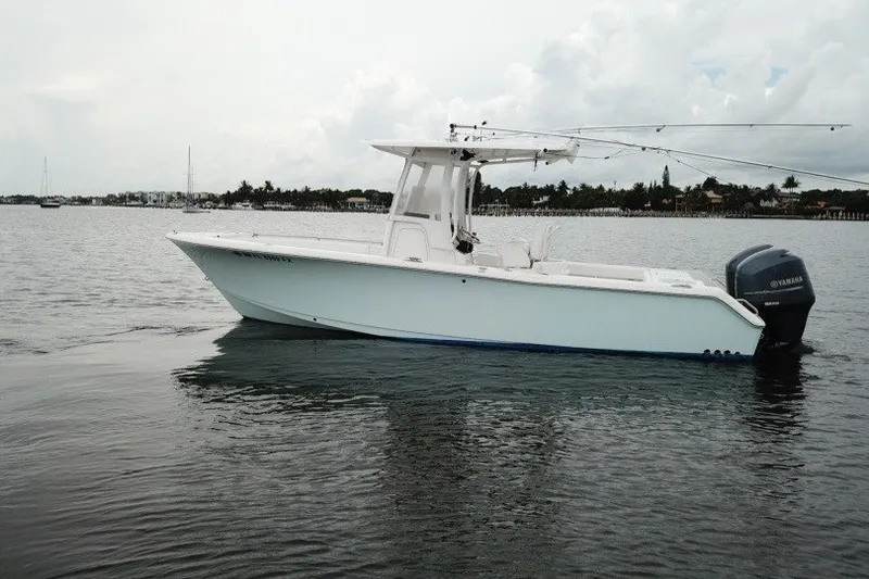 Slide: The Image of 2014 Sea Hunt Gamefish 25 boat on calm water, featuring a sleek design and Yamaha engine. - 2