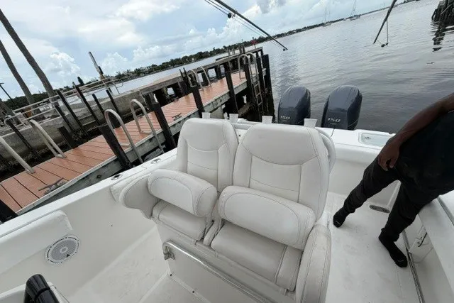 Slide: The Image of 2014 Sea Hunt Gamefish 25 boat with dual engines docked by a pier. - 14