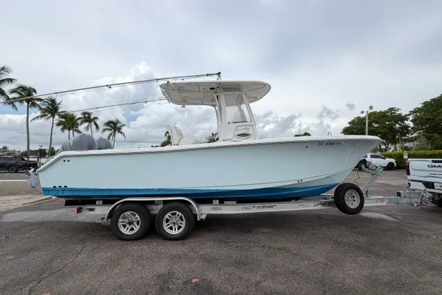 Slide: The Image of 2014 Sea Hunt Gamefish 25 boat on trailer, parked outdoors with palm trees in background. - 7