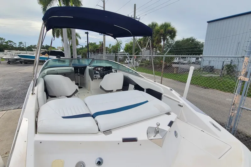 Slide: The Image of 2005 Regal 2200 Bowrider boat with white seating and blue canopy in a marina setting. - 15