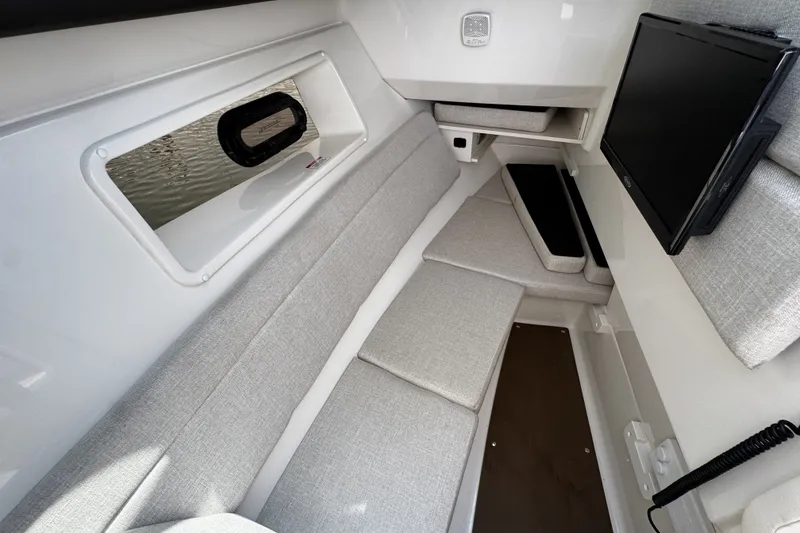 Slide: The Image of 2021 Sea Ray SLX 350 Outboard cabin interior with gray seating and a mounted TV. - 19