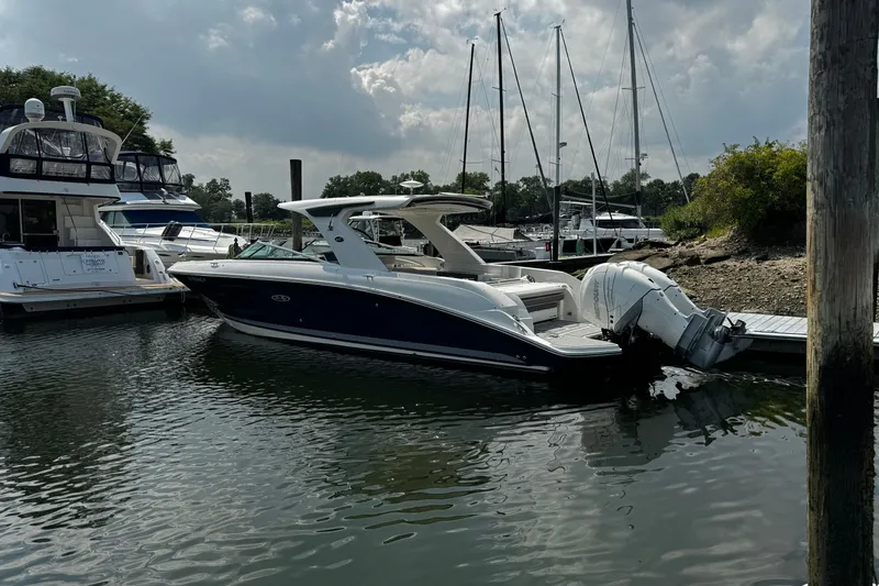 Slide: The Image of 2021 Sea Ray SLX 350 Outboard docked at a marina with sailboats in the background. - 1