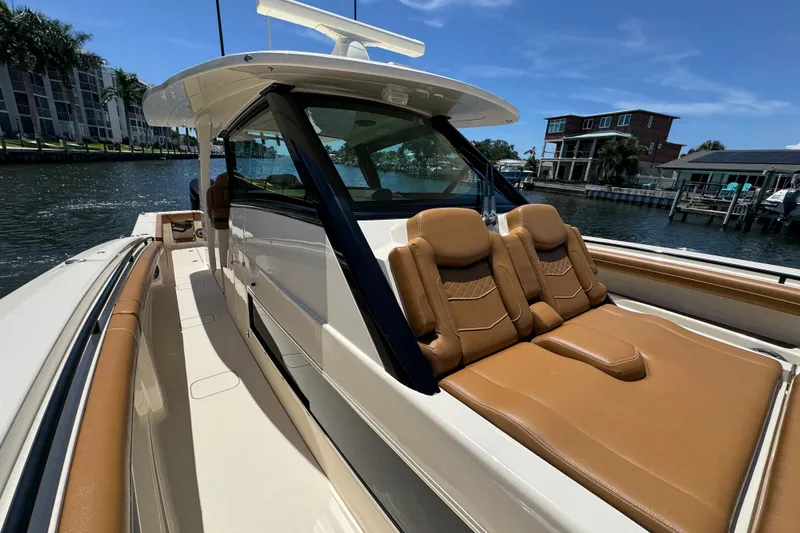 Slide: The Image of 2021 Scout 425 LXF luxury boat with tan seating, docked by waterfront homes. - 27