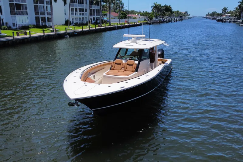 Slide: The Image of 2021 Scout 425 LXF boat cruising on a sunny canal with waterfront homes. - 20
