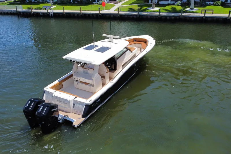 Slide: The Image of 2021 Scout 425 LXF boat cruising on a calm waterway near a residential area. - 16
