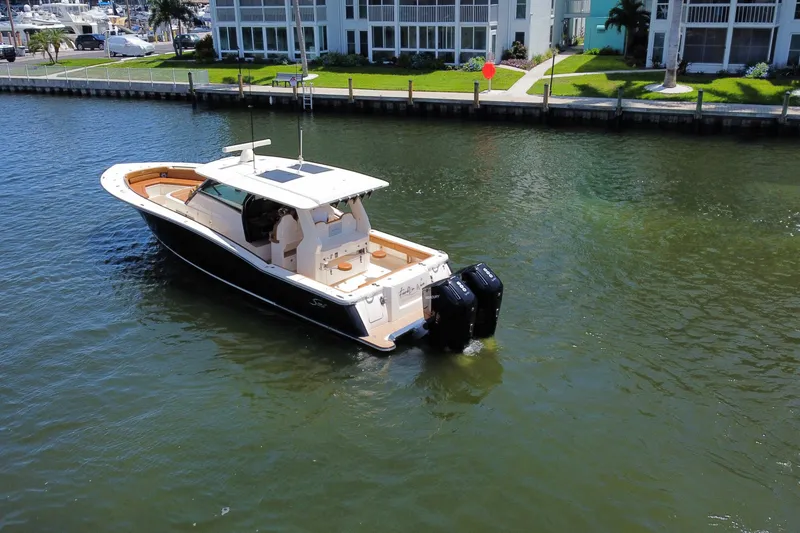 Slide: The Image of 2021 Scout 425 LXF boat cruising on a calm waterway near waterfront homes. - 15