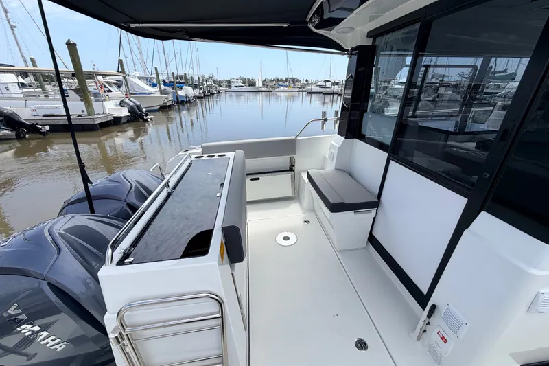 Slide: The Image of 2026 Jeanneau NC 895 Sport Series 2 boat interior at marina, featuring seating and Yamaha engines. - 24