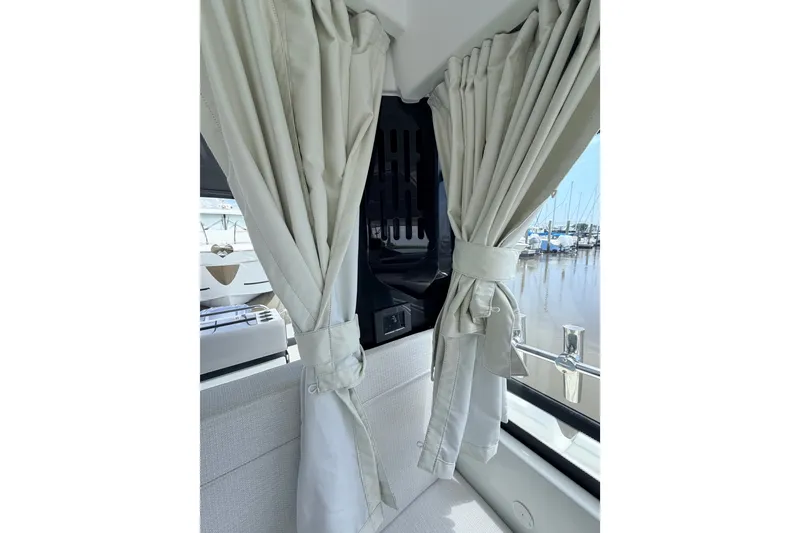 Slide: The Image of Interior view of 2026 Jeanneau NC 895 Sport Series 2 with elegant curtains and marina backdrop. - 35