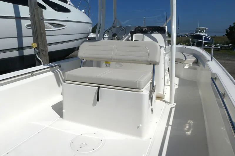 Slide: The Image of 2027 Boston Whaler 190 Montauk boat interior with seating and console, docked outdoors. - 10