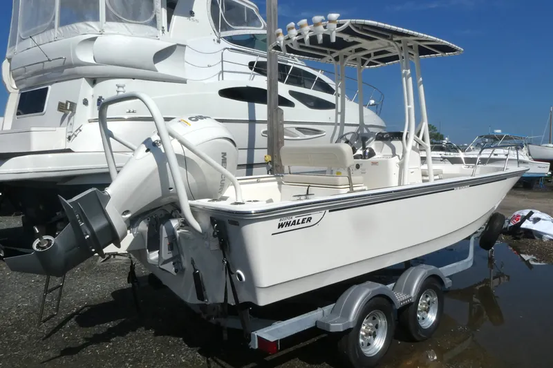 Slide: The Image of 2027 Boston Whaler 190 Montauk boat on trailer, parked near other vessels. - 1