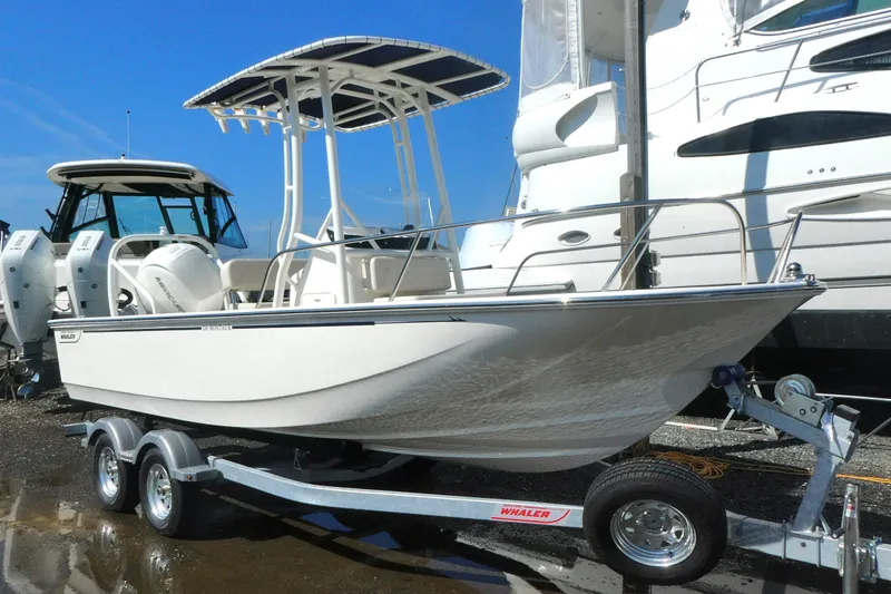 The Image of 2027 Boston Whaler 190 Montauk boat on trailer, parked near other vessels. - 0