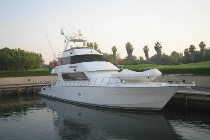 Slide: The Image of 1996 Hatteras yacht docked in serene marina with palm trees in background. - 42