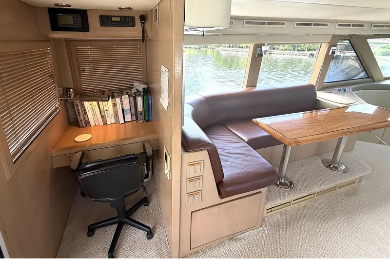 Slide: The Image of 1996 Hatteras yacht interior with desk, chair, and dining area overlooking water. - 27