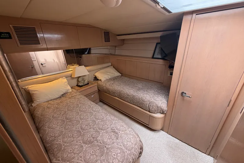 Slide: The Image of 1996 Hatteras yacht cabin with twin beds, wooden interior, and cozy lighting. - 17