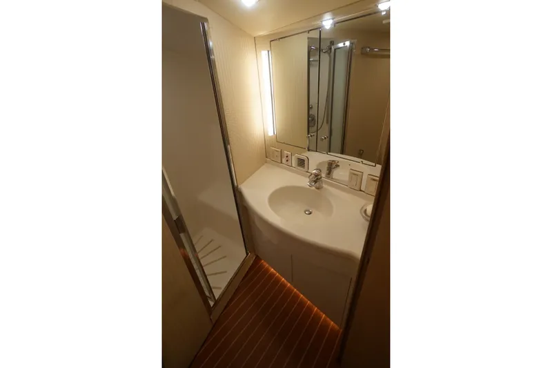 Slide: The Image of Compact bathroom on a 1996 Hatteras yacht with modern fixtures and wood flooring. - 16
