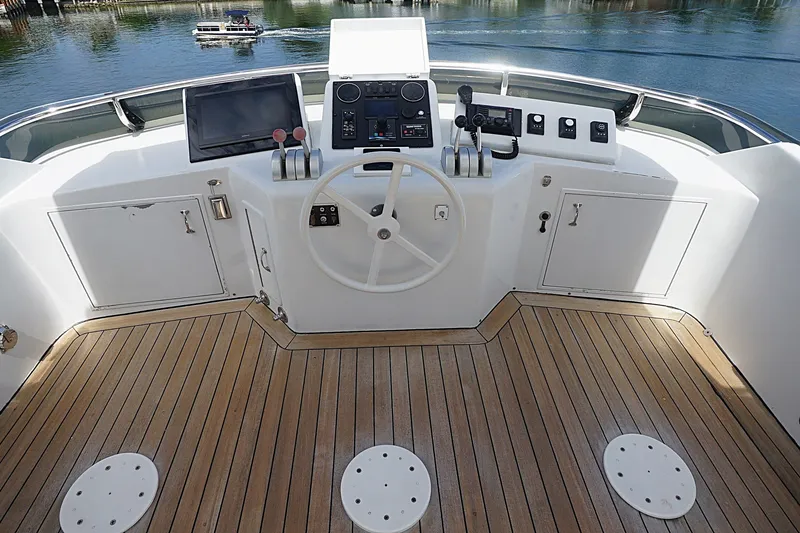 Slide: The Image of 1996 Hatteras yacht helm with wooden deck, steering wheel, and navigation controls. - 30