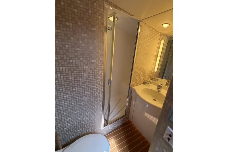 Slide: The Image of 1996 Hatteras yacht bathroom with modern fixtures, mosaic tiles, and compact shower. - 18