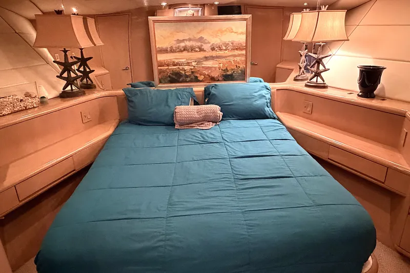 Slide: The Image of Luxurious 1996 Hatteras yacht bedroom with teal bedding, elegant lamps, and nautical decor. - 15